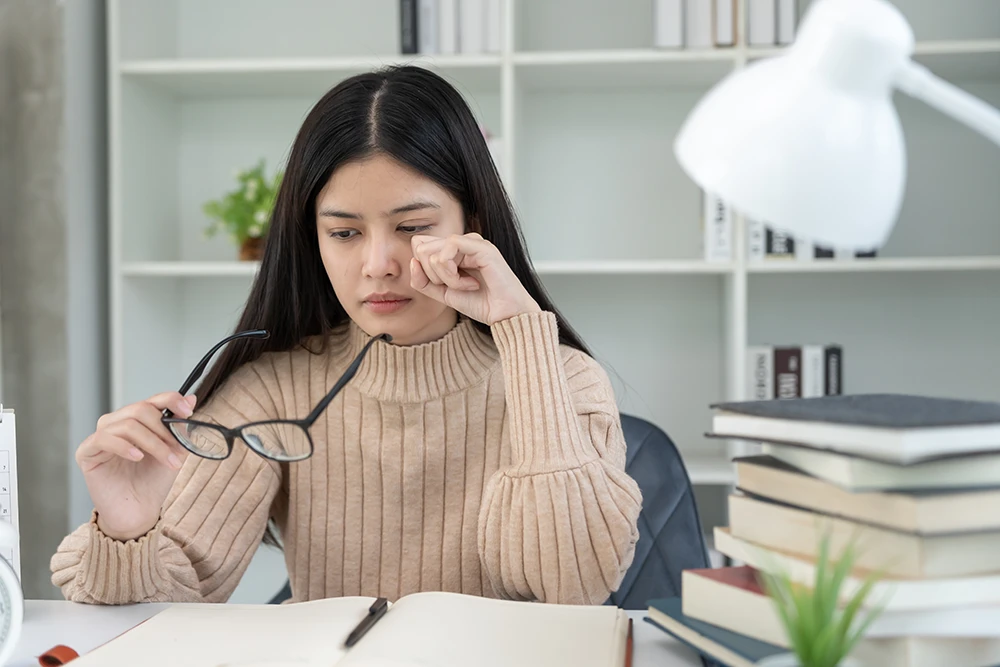 gritty-eyes a woman taking off her glasses and rubbing her eye due to irritation