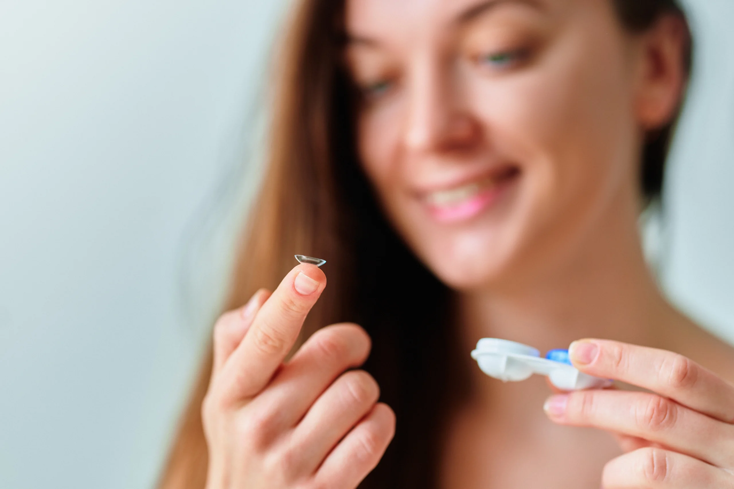 A cheerful young woman putting in a contact lens.