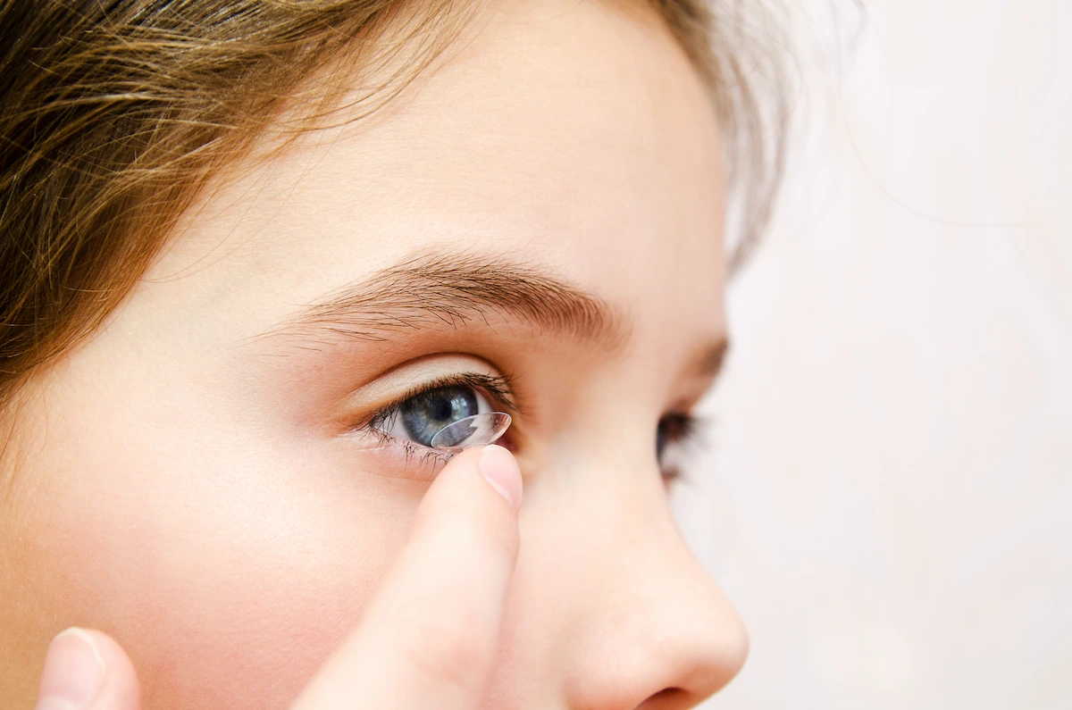 Child placing contact lens in eye